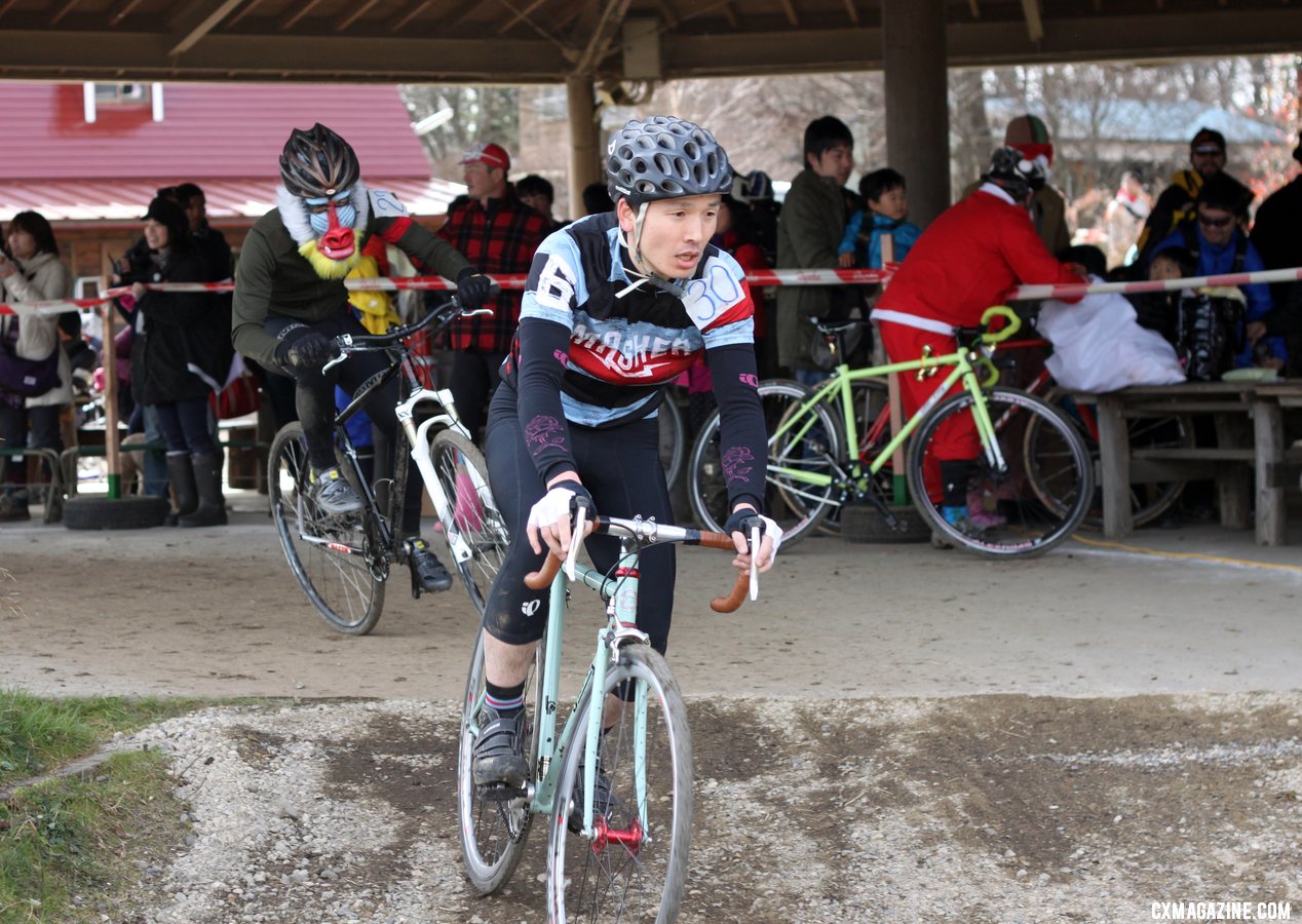 A singlespeeder fends of a costumed racer, while Santa gives back. 2011 Nobeyama, Japan UCI Cyclocross Race. © Cyclocross Magazine