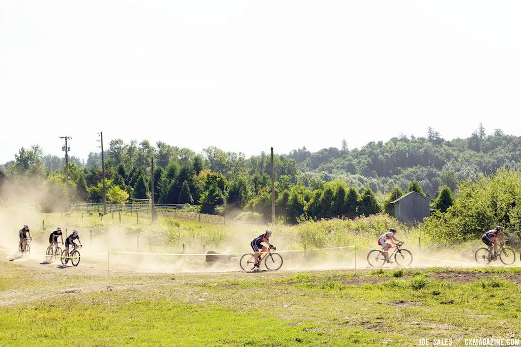 Riders kick up dust as they pedal across the field. © Joe Sales