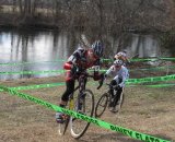 Kat Statman grinds up a short steep hill by the river ahead of Shawn Adams