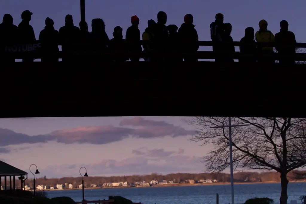 Silhouetted spectators watch the race from the bridge overlooking the finish line. © Todd Prekaski