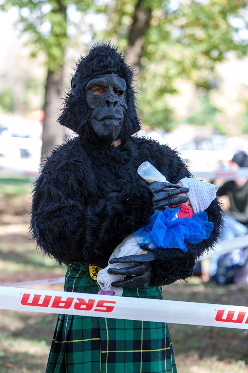 Shamrock Cycles racer James Foster nurses a baby in a gorilla costume. © Kent Baumgardt