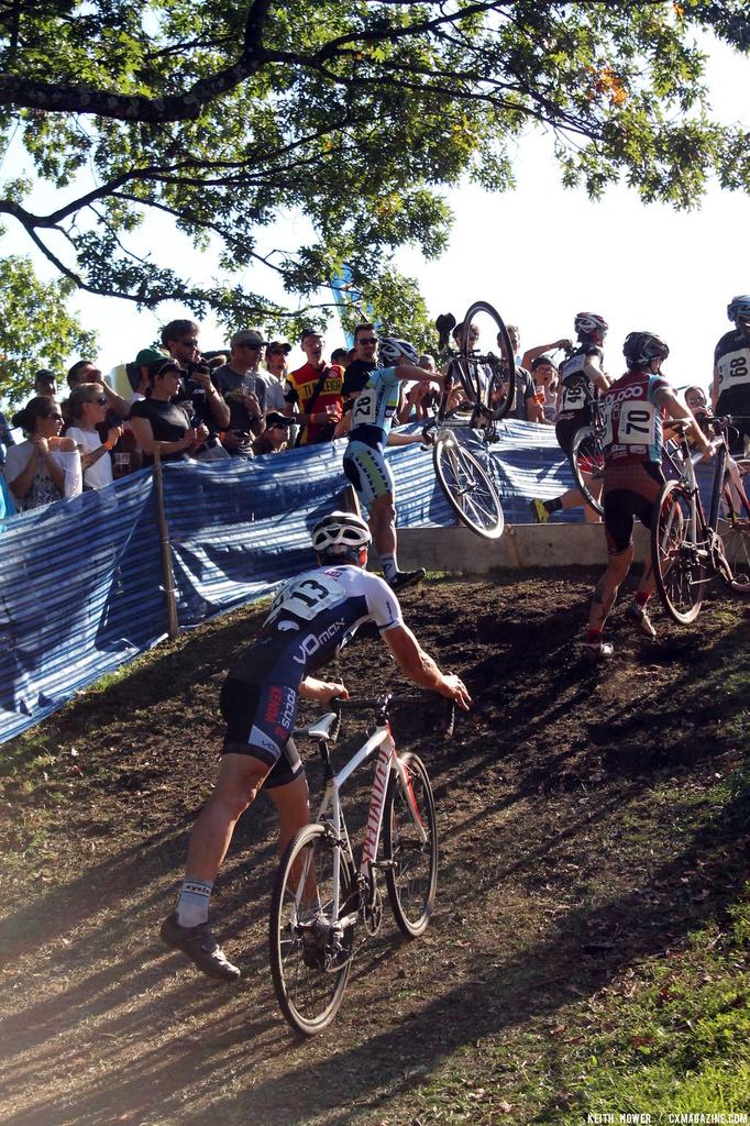 A rider has difficulty getting his bike over the barrier. © Cyclocross Magazine