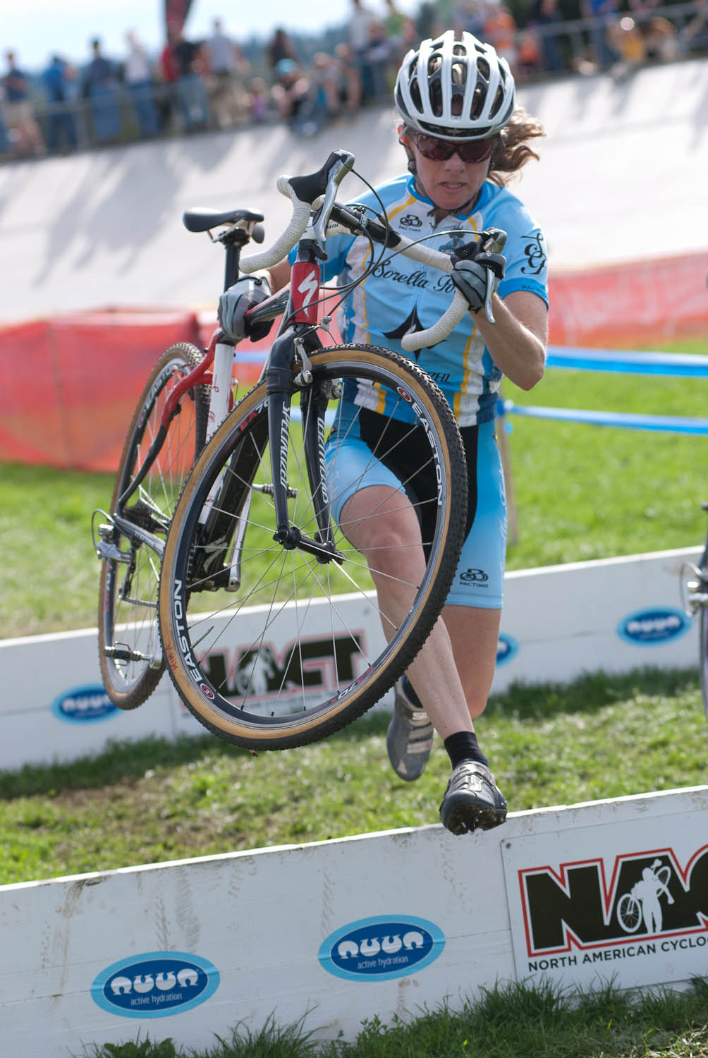 One of the women\'s cat 3/4 racers leaps over the barriers. © Karen Johanson