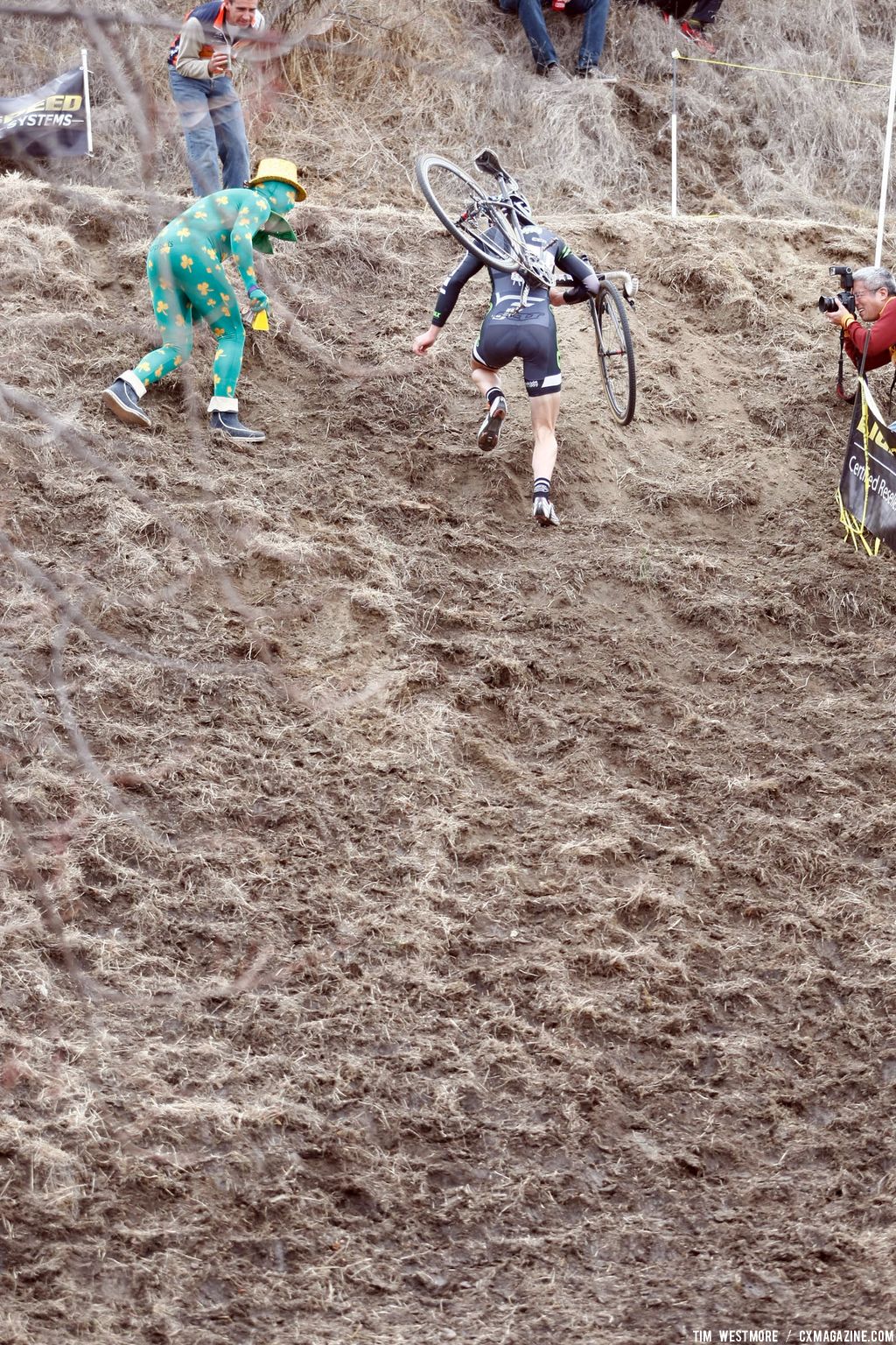 An Elite racer receives attention from the Green-Shamrock Man at the top of the run-up © Tim Westmore