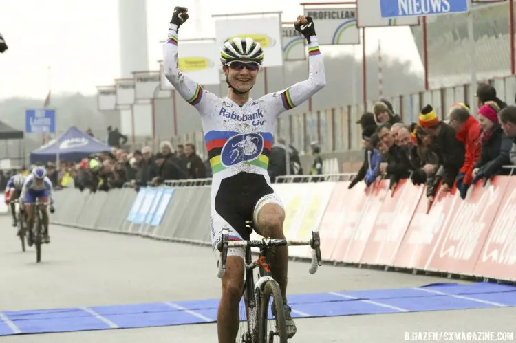 A victorious Vos puts her arms up as Nash sprints behind. © Bart Hazen/Cyclocross Magazine