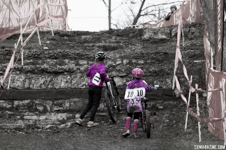 Gretchen Wayman and Mckenna Wilkins, both in Purple and from Texas, trying to figure out how to scale the limestone wall with their heavy bikes. © Cyclocross Magazine