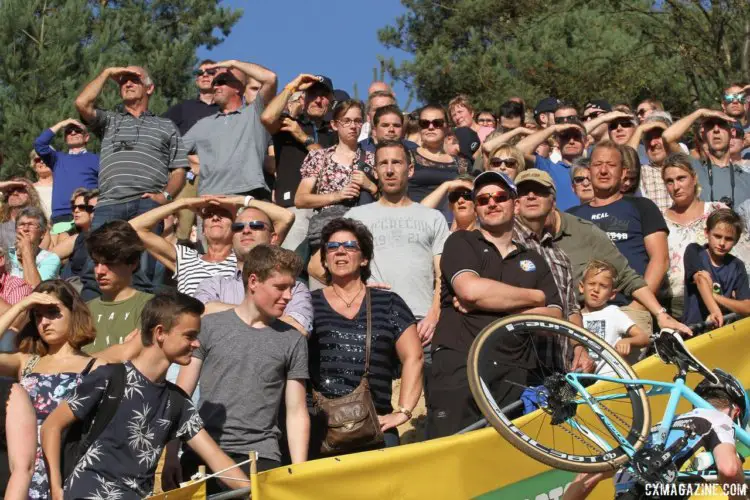 Fans watch the big screen as a rider runs by. 2017 Superprestige Zonhoven. © B. Hazen / Cyclocross Magazine