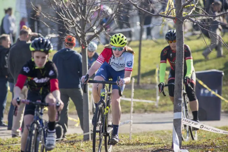 Girls 9-14 Chicago Cross Cup and State Champion Chloe Yoder weaves through a gauntlet of trees and women competing in the adult cat 4-5 race which occurs simultaneously with the young juniors race. 2017 Chicago Cross Cup #11, Montrose Harbor Illinois State Championships. © 2017 Matthew Gilson