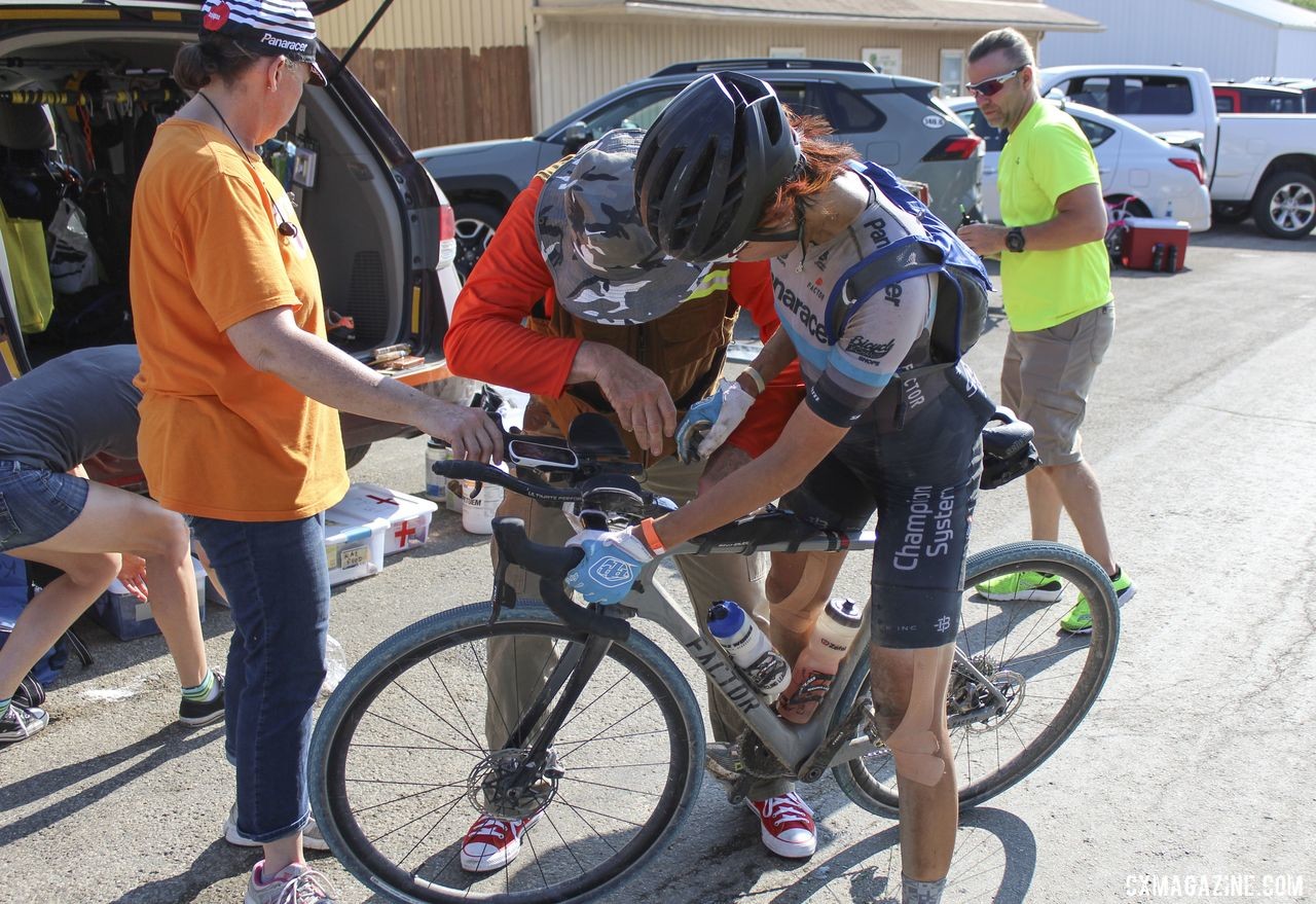 Dan Szokarski helps restock Takeshita's top tube bag while Becky Cummings helps hold her bike. 2019 Dirty Kanza 200, Panaracer / Factor p/b Bicycle X-Change Checkpoint 1. © Z. Schuster / Cyclocross Magazine