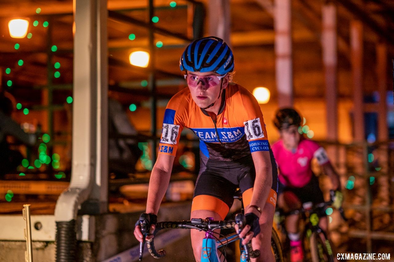 Sophie Russenberger passes through one of the barns during the night race. 2019 Jingle Cross Weekend. © Drew Coleman