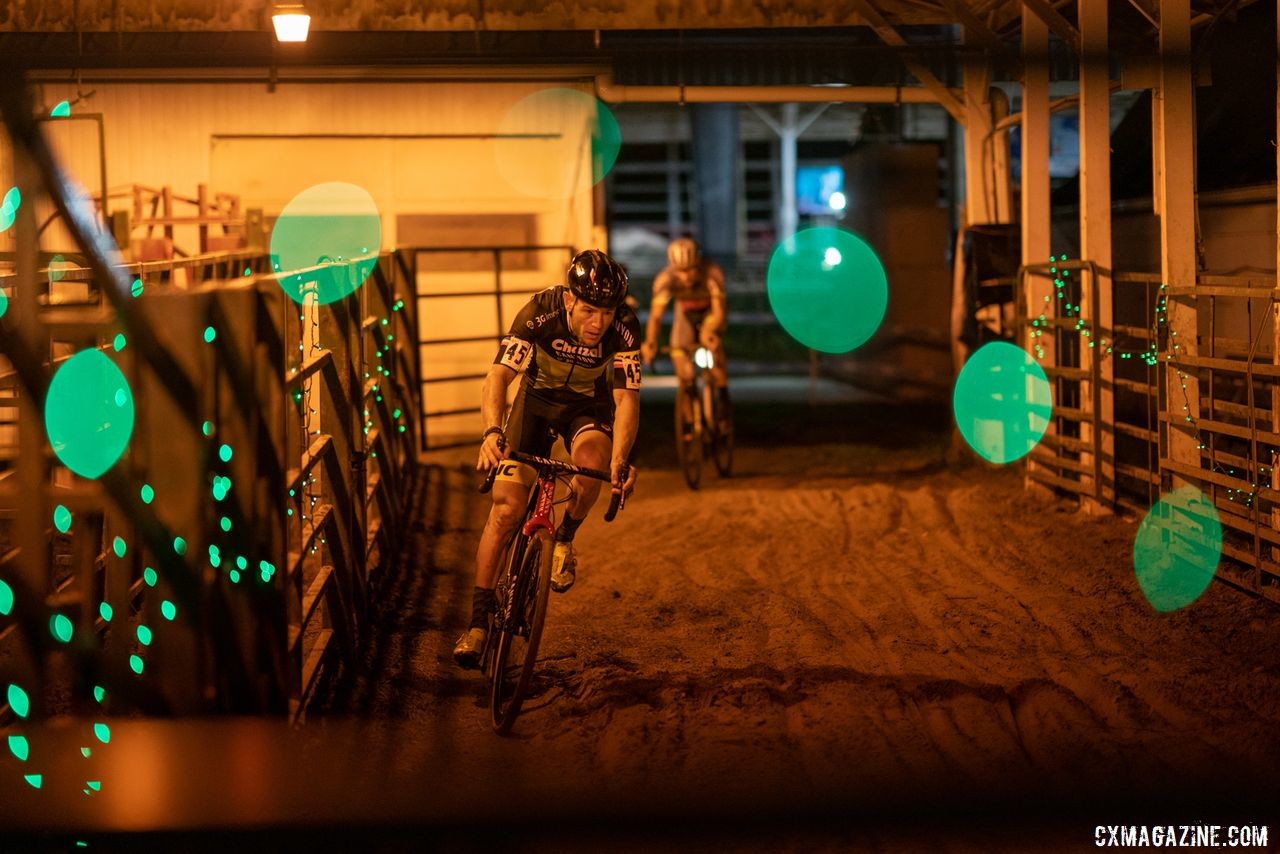 Steve Chainel passes through one of the barns during Friday night's race. 2019 Jingle Cross Weekend. © Drew Coleman