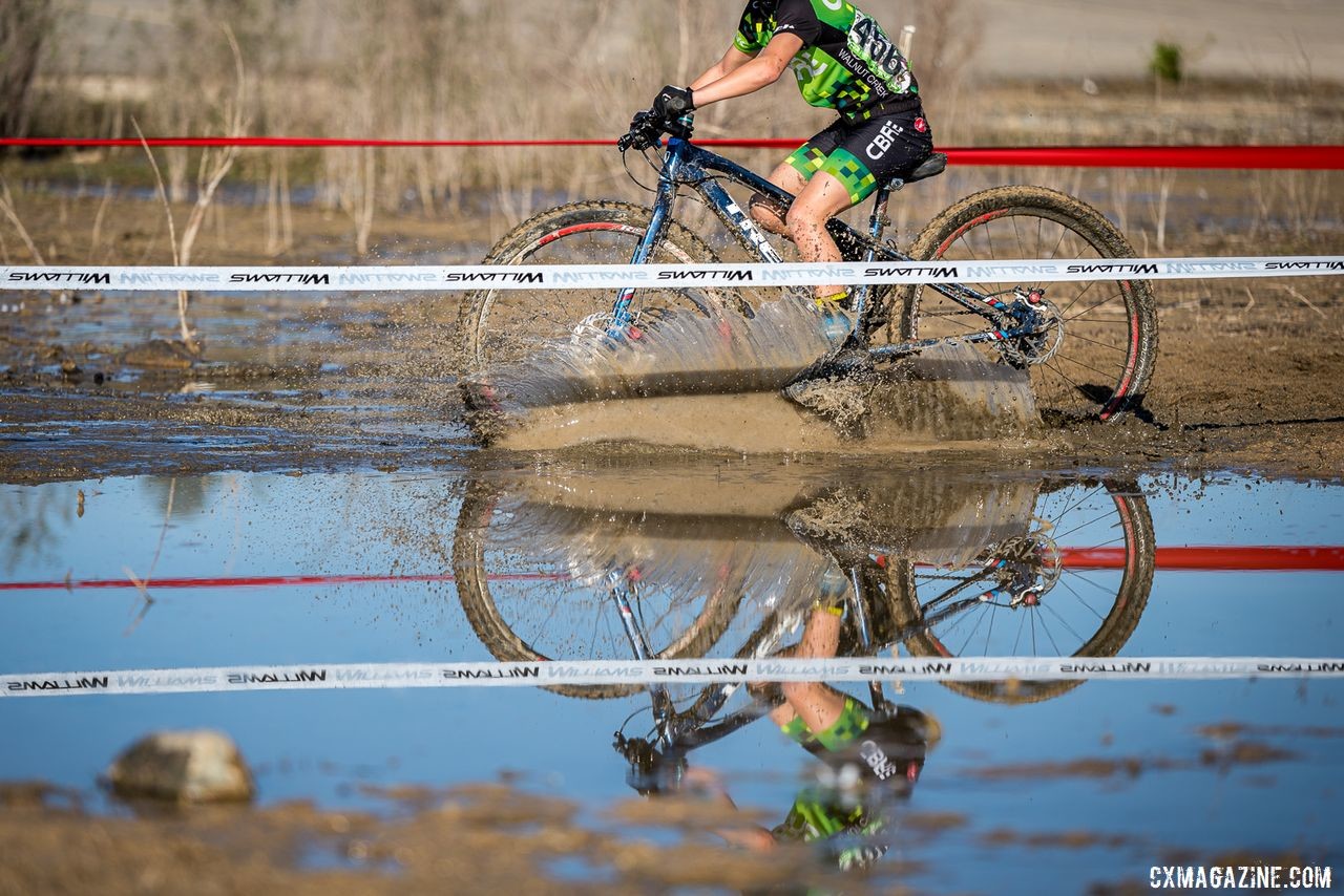 A Junior (and his reflection) crosses one of the many puddles on the Granite Beach course. 2019 Sacramento CX Granite Beach, California. © Jeff Vander Stucken