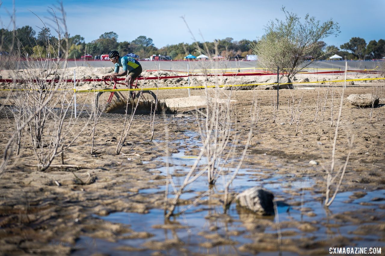 Fergus Tanaka crosses the lakebed with the boat launch and start/finish straight in the background. 2019 Sacramento CX Granite Beach, California. © Jeff Vander Stucken