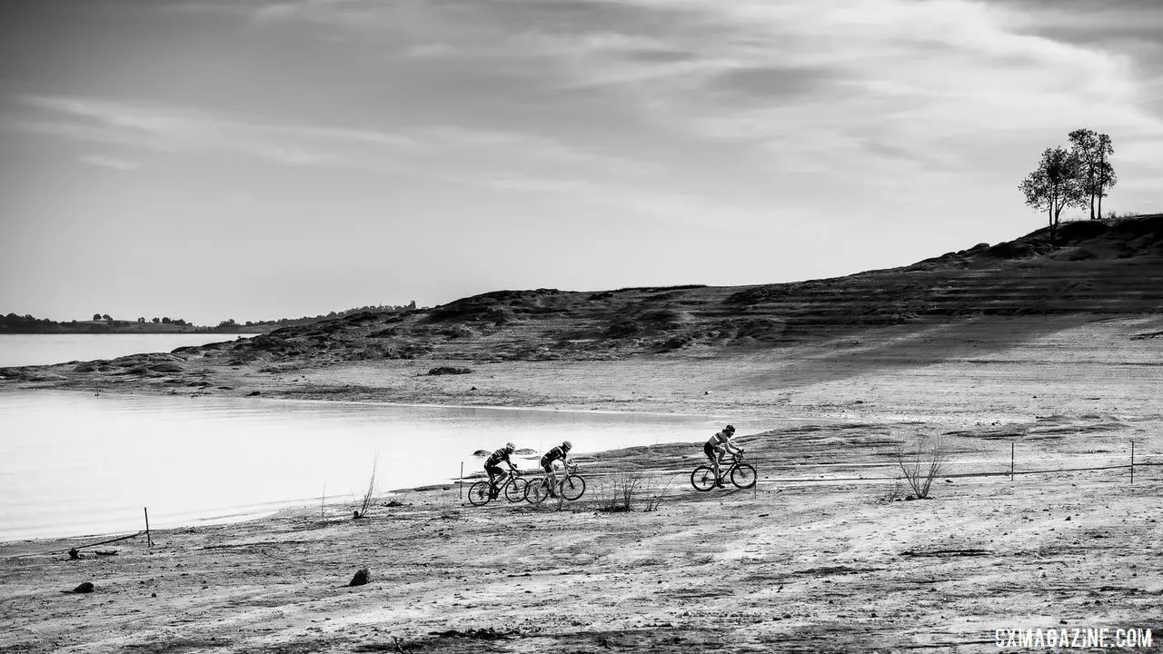 The Mens A podium (Jonathan Baker, Nathan Barton, and Tim Bolton) race along eht edge of Folsom Lake 2019 Sacramento CX Granite Beach, California. © Jeff Vander Stucken